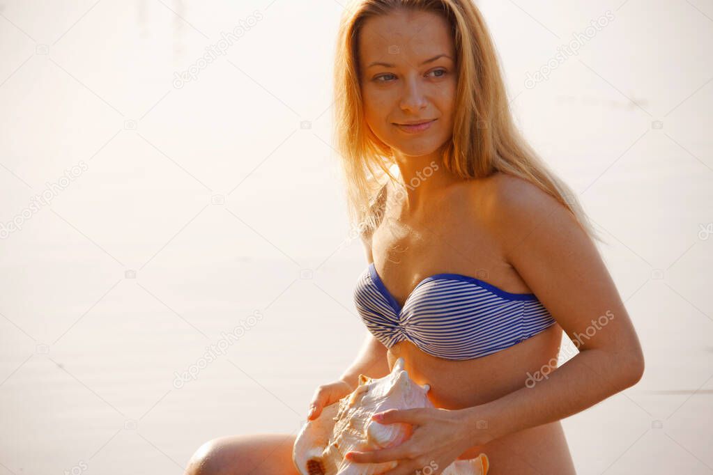 portrait of a girl with a sea shell near the water at sunrise 2020