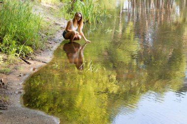 2020 ormanındaki küçük bir nehrin kıyısında bir kız.