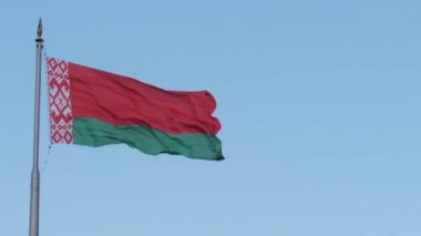 Beyaz Rusya bayrağının mavi gökyüzüne karşı rüzgarda sallanan sembolleri.