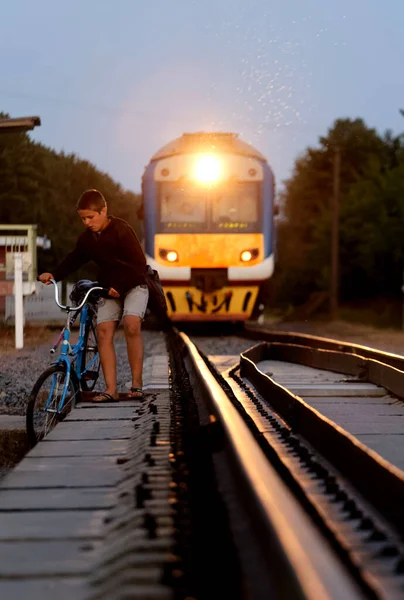 危险的骑自行车男孩在2020年火车前的铁路上 — 图库照片