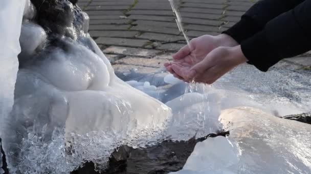 A água derrama de uma fonte no homem do inverno pega a água em sua palma — Vídeo de Stock