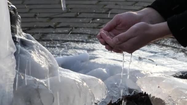 Agua se derrama de una primavera en invierno el hombre recoge el agua en su palma — Vídeos de Stock