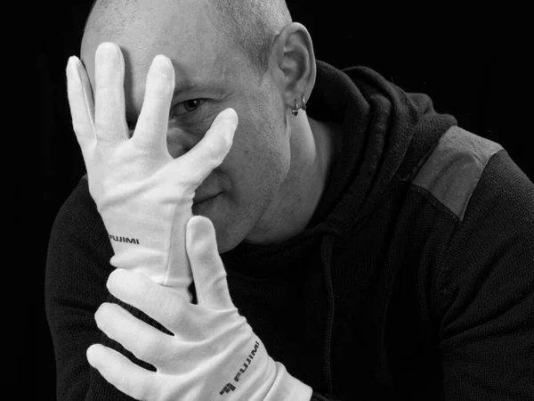 bw portrait of a bald man in white gloves on a black background 2021