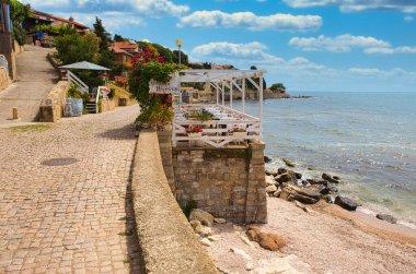NESSEBAR, BULGARIA, 18 Haziran 2016: Samimi kafeler ve küçük plajlı Nessebar gezinti alanı. 2021