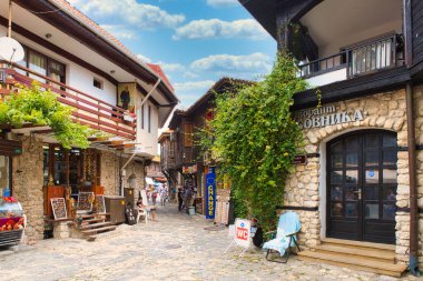 NESSEBAR, BULGARIA, 18 Haziran 2016: turistler eski Nessebar kentinin sokaklarındaki hediyelik eşya dükkanlarını ziyaret ediyorlar. 2021