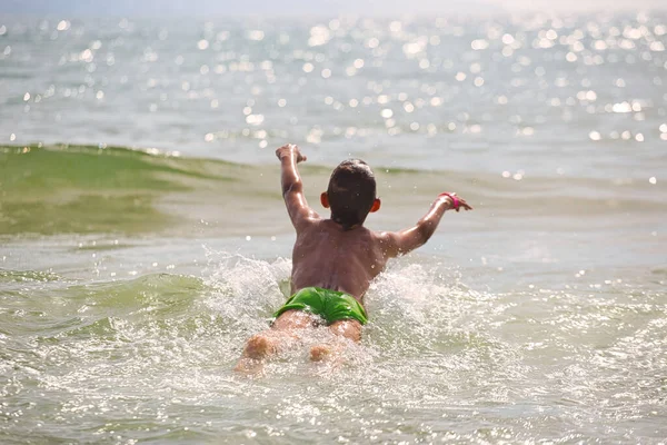 child swims in the sea waves on the beach 2021