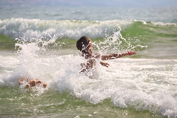 child swims in the sea waves on the beach 2021