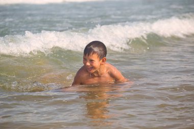 Çocuk 2021 plajındaki deniz dalgalarında yüzüyor.