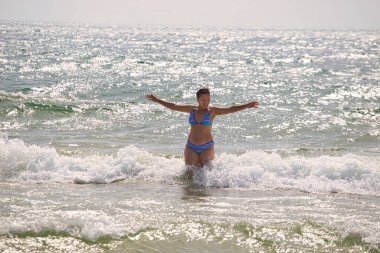 2021 plajında deniz dalgaları içinde yıkanan bir kadın.