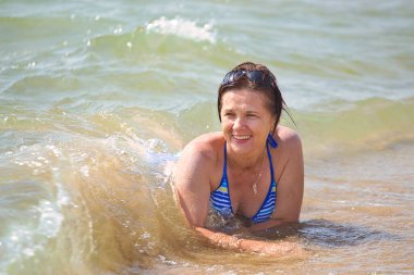 2021 plajında deniz dalgaları içinde yıkanan bir kadın.