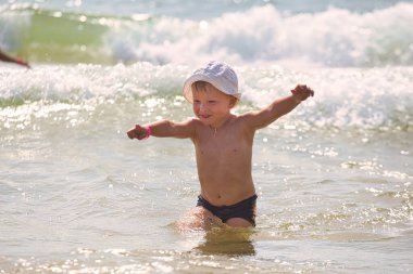 Çocuk 2021 plajındaki deniz dalgalarında yüzüyor.