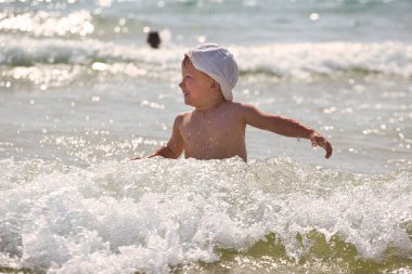 Çocuk 2021 plajındaki deniz dalgalarında yüzüyor.