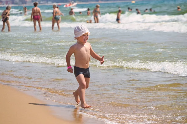 child swims in the sea waves on the beach 2021