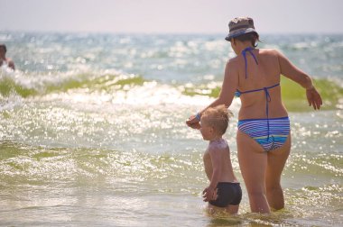 Aile 2021 plajında deniz dalgalarında yüzer.