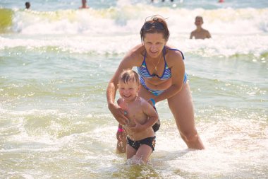 Aile 2021 plajında deniz dalgalarında yüzer.