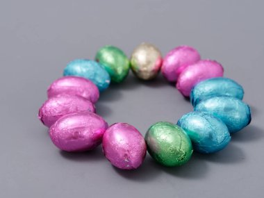 2021 'in gri arka planında paskalya yumurtası şeklinde folyoyla çikolatalı şekerler