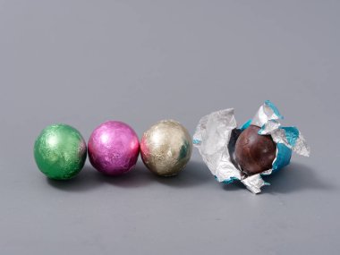 2021 'in gri arka planında paskalya yumurtası şeklinde folyoyla çikolatalı şekerler