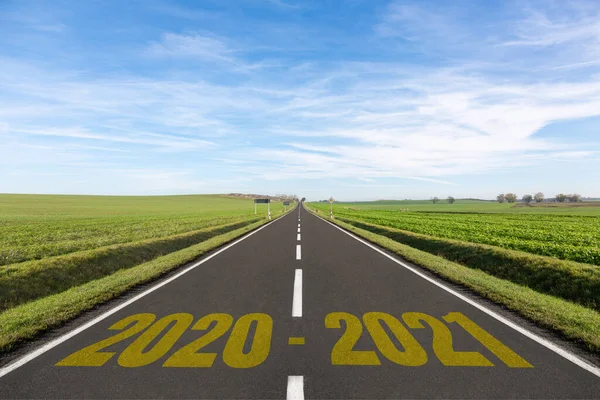 Yeşil tarlalarla çevrili boş yol ve 2020-2021 yılları yazılı.
