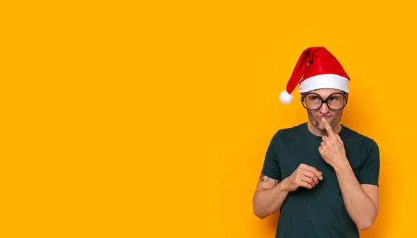 Noel kulübesi ve komik bir ifadesi olan genç bir adam.