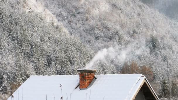 Casa de aldeia com uma chaminé para fumar no fundo da montanha de inverno — Vídeo de Stock