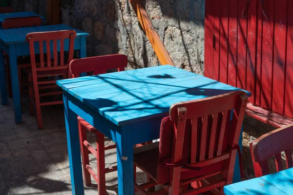 Old wooden furniture. Blue table and red chairs outdoor in small village yard. Vintage and retro concept.