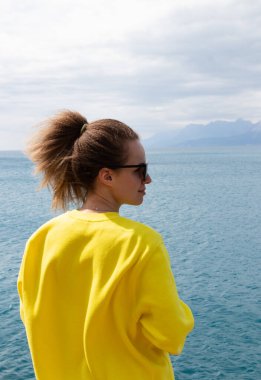 Back view portrait of a pretty woman on the sea background. Travel, tourism, and wellness concept