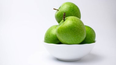Yeşil elmalar beyaz tabakta, arka planda, izole edilmiş..