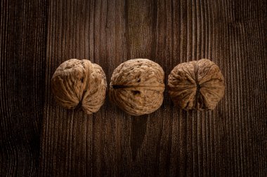 Nutkahverengi tek renkli arka plan. Kahverengi ahşap yüzeyde birkaç ceviz var..