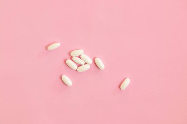 Beyaz haplar, pembe arka planda ağrı kesiciler.. 