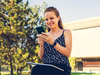 Esmer kadın yazın açık havada akıllı telefonunu kullanıyor.