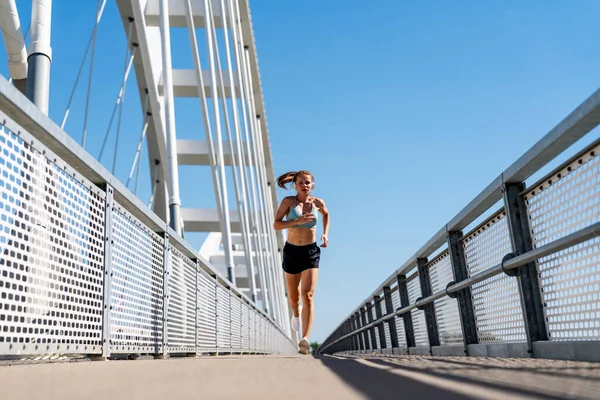 Şehir köprüsünde koşan atletik kadın