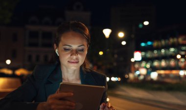 Şehir kadını gece sokakta dijital tablet kullanıyor.