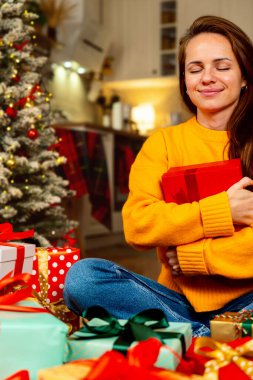 Female hugging gift box in Christmas morning.