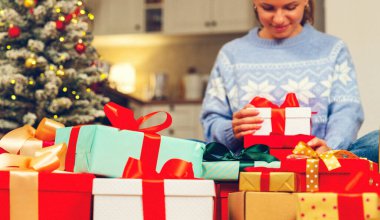 Noel hediye kutuları, arka planda kumlu efektli bir kadın açılışıyla yakın çekim..