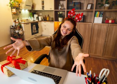 Ren geyiği boynuzları takan neşeli kadın Noel 'de arkadaşlarıyla sanal bir toplantı yapıyor..