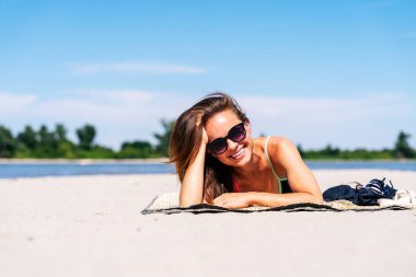 Sıcak yaz gününde kumsalda eğlenen gülümseyen bir kadın.