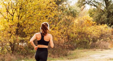 Sonbahar doğasında kadın koşucu eğitiminin arka görüntüsü..