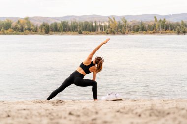 Sonbahar mevsiminde nehir kıyısında egzersiz yapan zinde bir kadın.