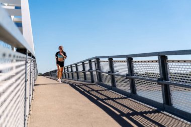 Şehir köprüsünde koşan modern bir kadın. Sağlıklı ve aktif yaşam tarzı.