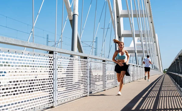 Şehir köprüsünde koşan modern bir kadın. Sağlıklı ve aktif yaşam tarzı.