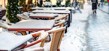Şehirde kış günü. Kış günü karla kaplı kafeterya masaları