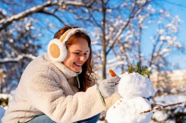 Neşeli kadın kışın açık havada kardan adam yapıyor..