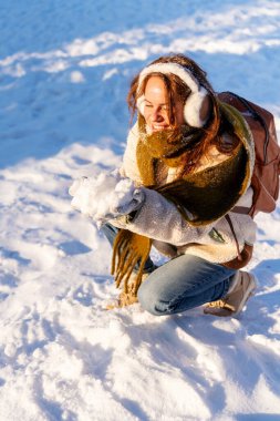 Mutlu genç kadın kışın açık havada taze kara dokunuyor.