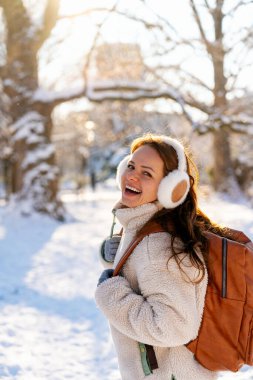 Mutlu genç bir kadın kışın şehir parkında geziniyor.