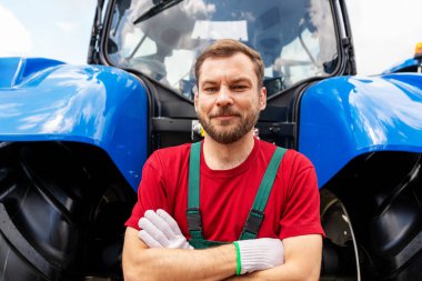 Çiftlik traktörünün yanındaki erkek tamircinin samimi portresi.