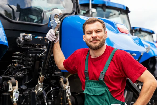 Tarım ekipmanları bayiliğinde traktörlerin yanındaki erkek tamirci.