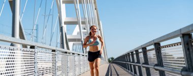 Kadın koşucu yazın şehir köprüsünde açık havada egzersiz yapıyor..