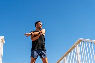 Genç yetişkin bir adam antrenmandan önce ısınıyor.,