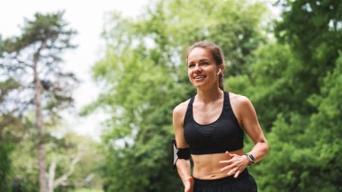 Şehir parkında sabah koşusu yaparken sağlıklı bir kadının portresi.