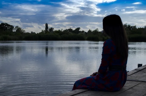 A silhueta da menina em um cais no lago — Fotografia de Stock